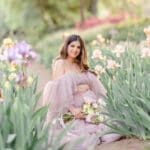 Xio Ponce Bay Area Family Photographer photo of pregnat mom in a Irish garden with a pink dress and flowers sitting down.